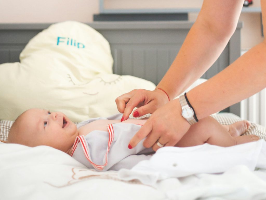Une maman change son bébé sur une table à langer